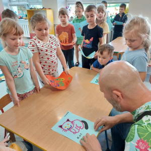 Osoba niewidoma za pomocą zmysłu dotyku odgaduje obrazki przygotowane przez dzieci. 