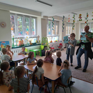 Osoba niewidoma tłumaczy dzieciom w jaki sposób przygotować wypukłe rysunki. 