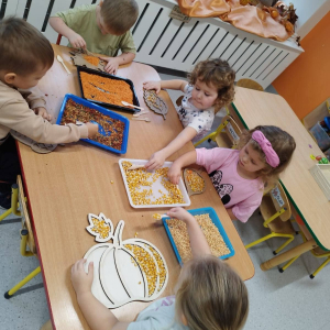 Dzieci rozwijają sprawność manualną przy pomocy wysypywanek w jesiennych kształtach, wypełnianych kaszą, kukurydzą, grochem i soczewicą.