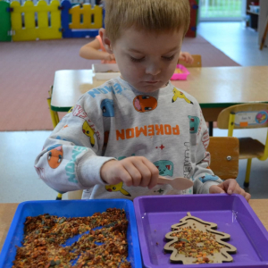 Dzieci rozwijają sprawność manualną przy pomocy wysypywanek w jesiennych kształtach, wypełnianych kaszą, kukurydzą, grochem i soczewicą.