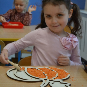 Dzieci rozwijają sprawność manualną przy pomocy wysypywanek w jesiennych kształtach, wypełnianych kaszą, kukurydzą, grochem i soczewicą.