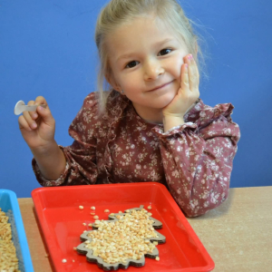 Dzieci rozwijają sprawność manualną przy pomocy wysypywanek w jesiennych kształtach, wypełnianych kaszą, kukurydzą, grochem i soczewicą.