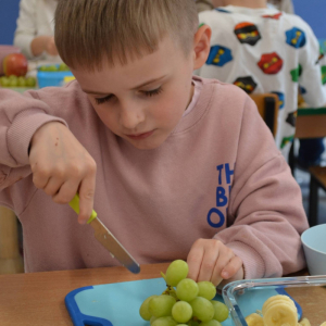 Dziecko przygotowuje sałatkę owocową.