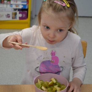 Dziecko przygotowuje sałatkę owocową.