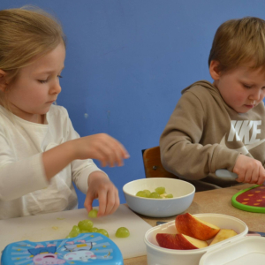 Dzieci przygotowują sałatkę owocową.