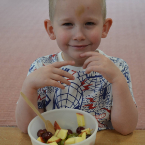 Dziecko przygotowuje sałatkę owocową.