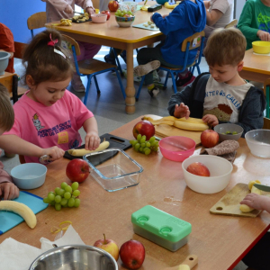 Dzieci przygotowują sałatkę owocową.