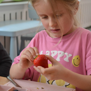 Dziecko przygotowuje sałatkę owocową.