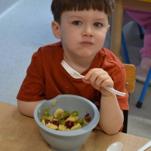 Dziecko przygotowuje sałatkę owocową.