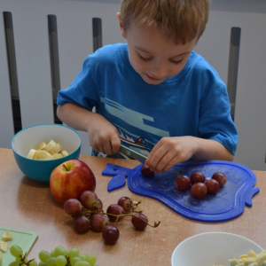 Dziecko przygotowuje sałatkę owocową.