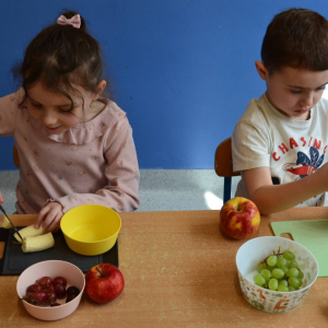 Dzieci przygotowują sałatkę owocową.