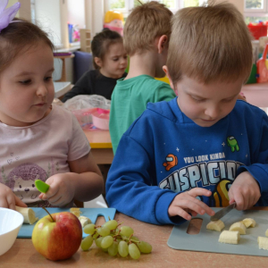 Dzieci przygotowują sałatkę owocową.