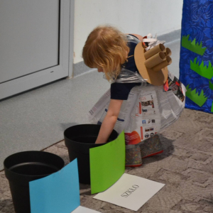 Dziecko segreguje śmieci do odpowiedniego kosza.