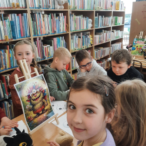 Dzieci biorą udział w lekcji bibliotecznej.