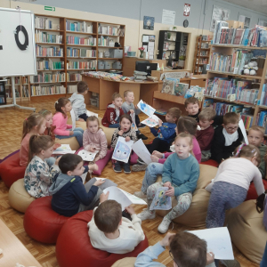 Dzieci biorą udział w lekcji bibliotecznej.